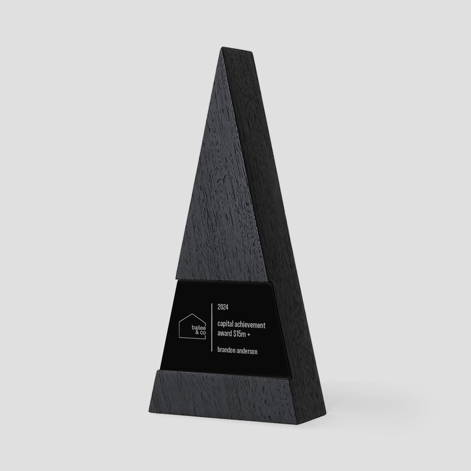 Figura Trigonum Award: black triangular trophy design with engraved plaque, symbolizing excellence. Crafted from walnut, maple, and metal, highlighting achievement and innovation.
