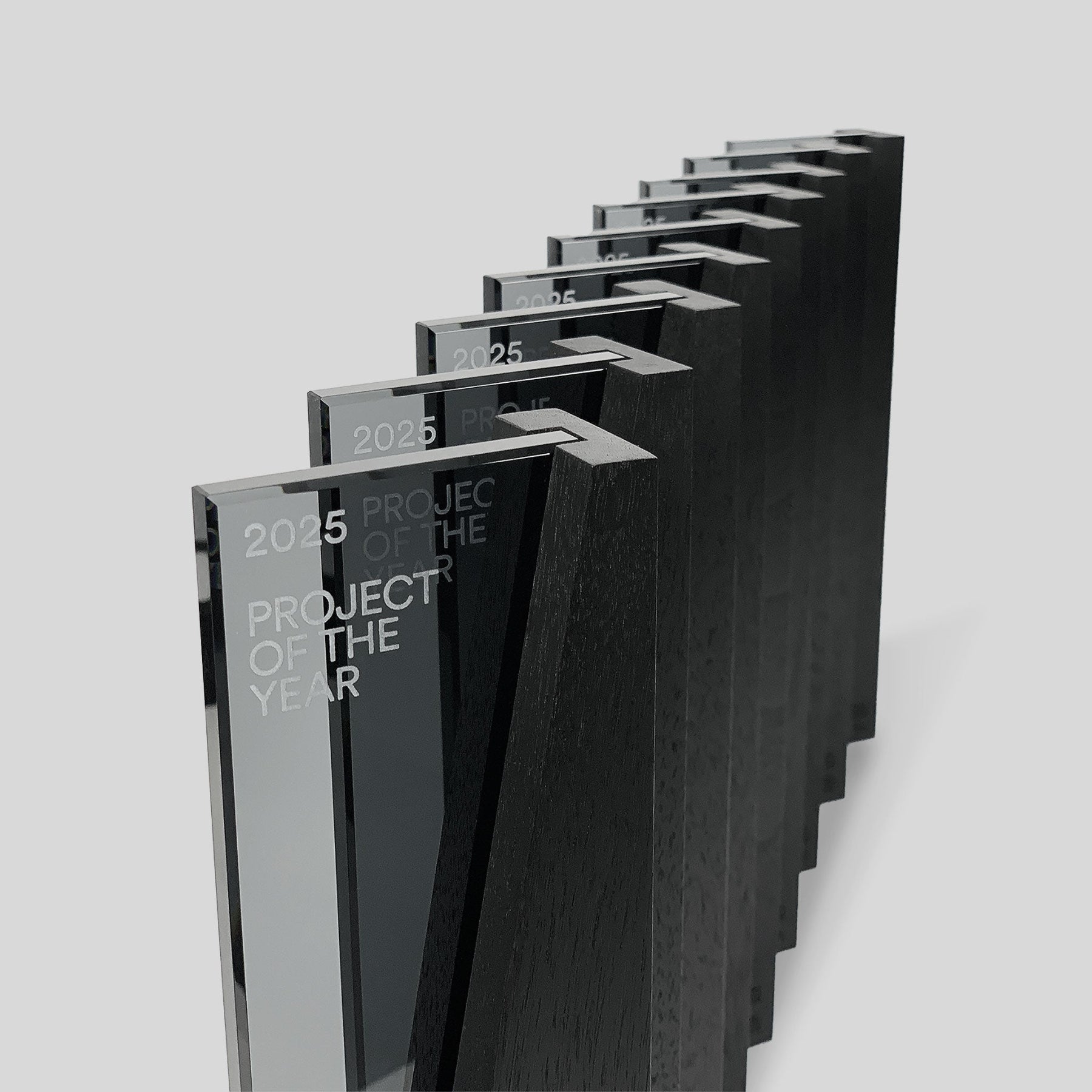 Series of modern DI/MI design awards by Trophyology, featuring interlocking glass and wood, engraved for 2025 Project of the Year honorees.