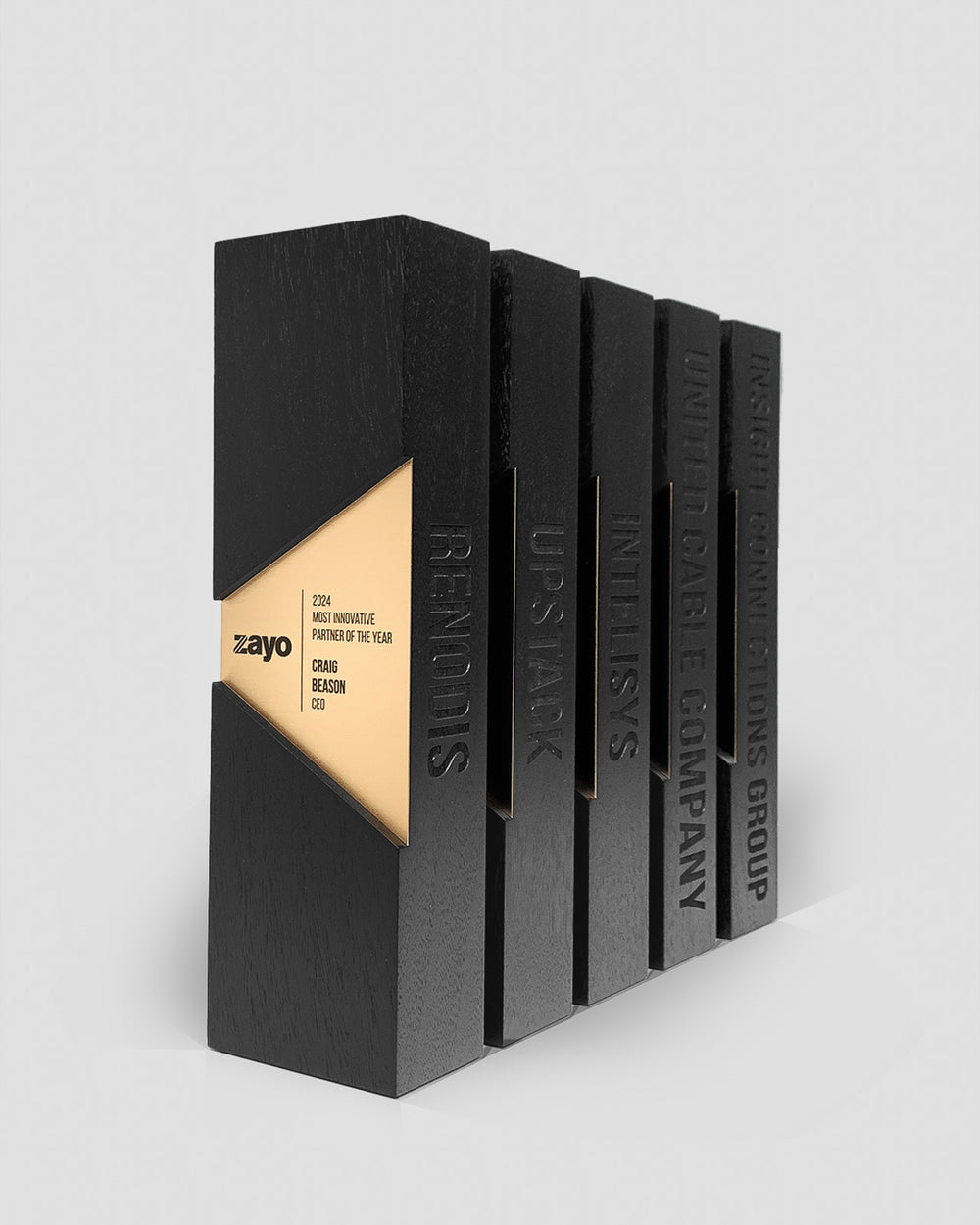Side profile of Trophyology’s Figura Trapezium Awards for Zayo showing deep edge engraving and sculptural walnut geometry for Innovation awards.