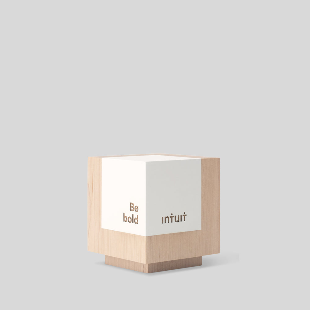 Geometria Award Cubus: a minimalist wooden cube with engraved text, exemplifying stability and precision, crafted from solid walnut or maple for elegant recognition. Architect-designed and artisan-crafted in the USA. 