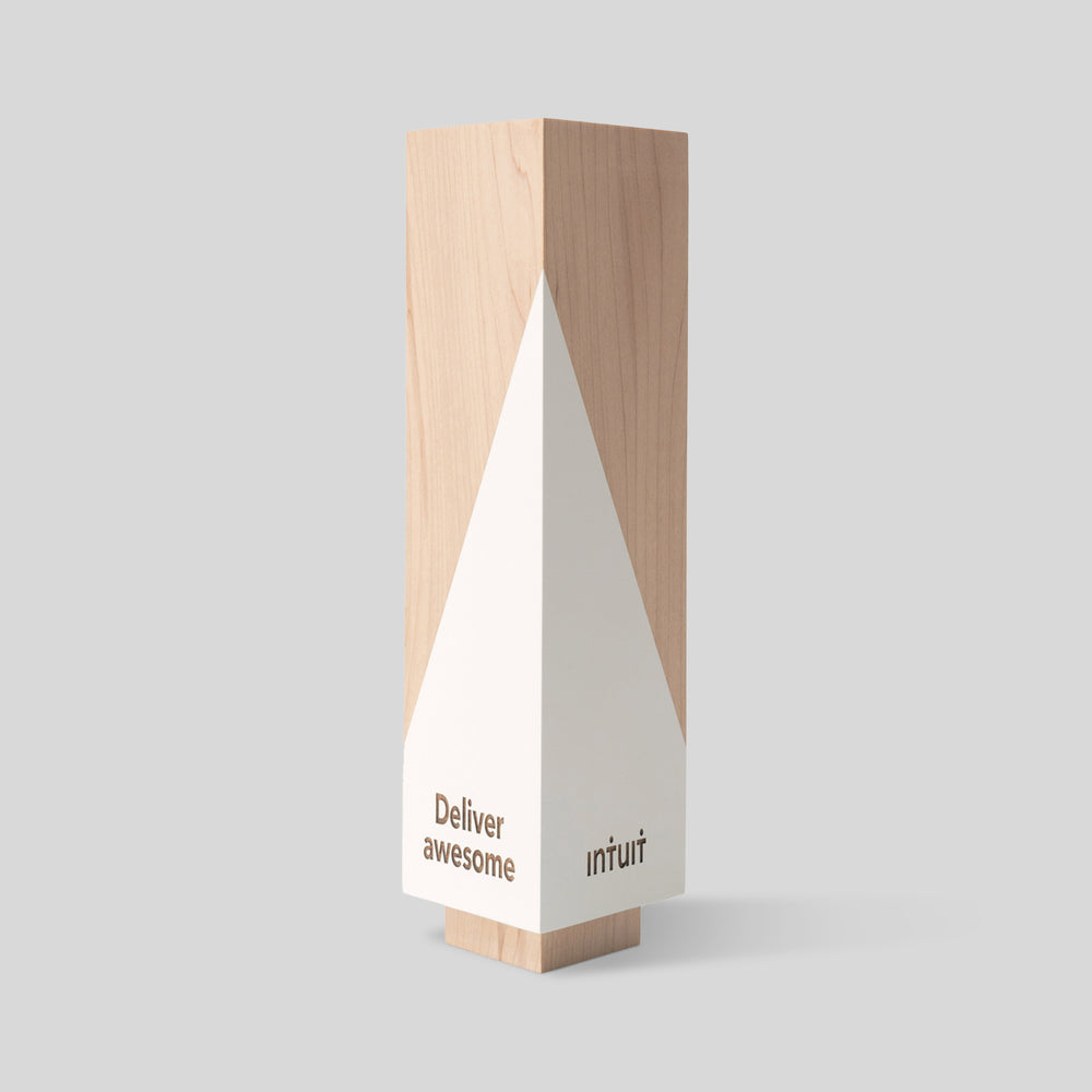 Geometria Award Triangulus features a white triangle design on a wooden surface, showcasing a minimalist style that symbolizes strength and precision.