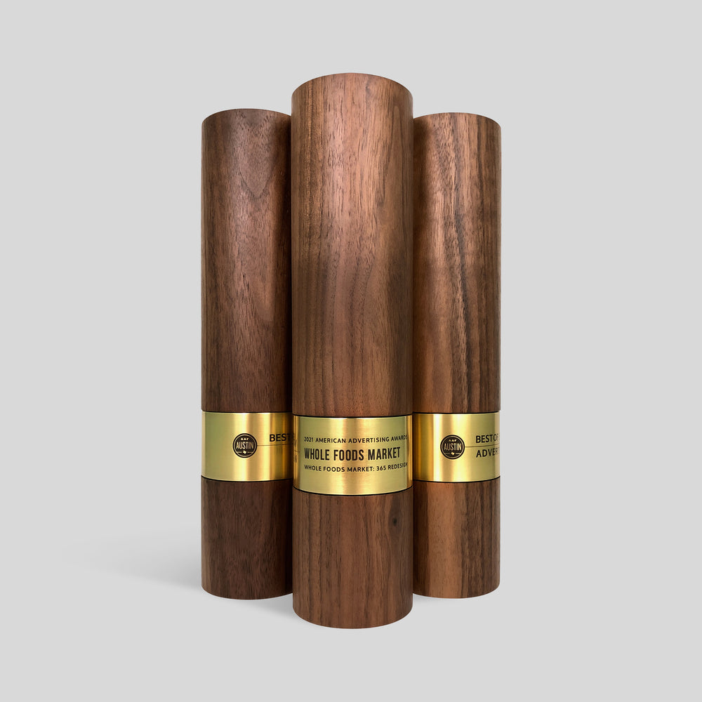 Stela Round Award | Large features wooden trophies, cylinders with gold nameplates, showcasing polished brass rings, symbolizing prestige and achievement. Unique, modern, architect-designed and artisan-crafted in USA. 