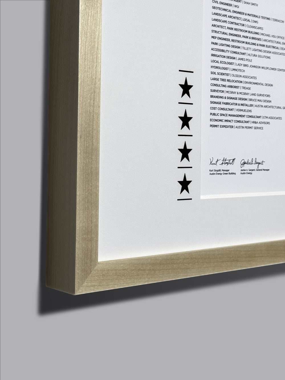 Award certificate framed in a maple wood frame with engraved stars on a white mat, showcasing a recognition certificate display, emphasizing the frame&#39;s close-up details and wood texture.
