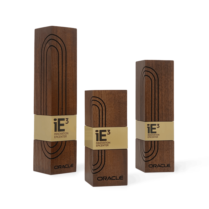 Modern executive awards for Oracle, crafted from walnut wood with engraved geometric patterns and gold metal accents. Customized, elegant recognition for innovation.