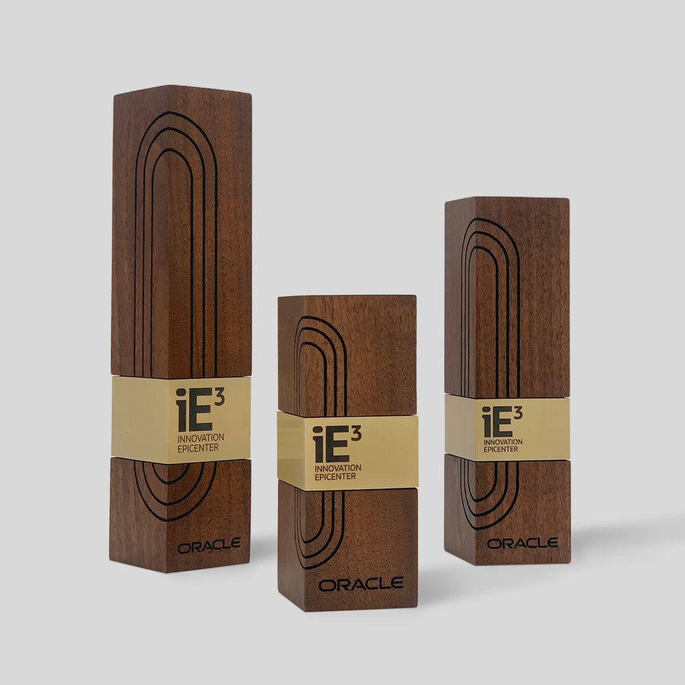 Modern executive awards for Oracle, crafted from walnut wood with engraved geometric patterns and gold metal accents. Customized, elegant recognition for innovation.