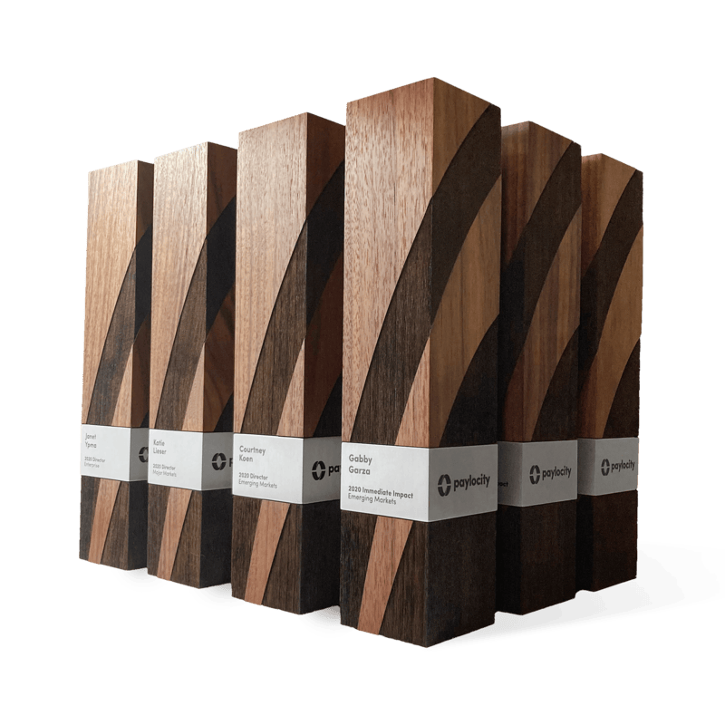 A collection of handcrafted executive awards made from rich wood with bold geometric engraving and metal nameplates. Modern, elegant recognition for excellence.
