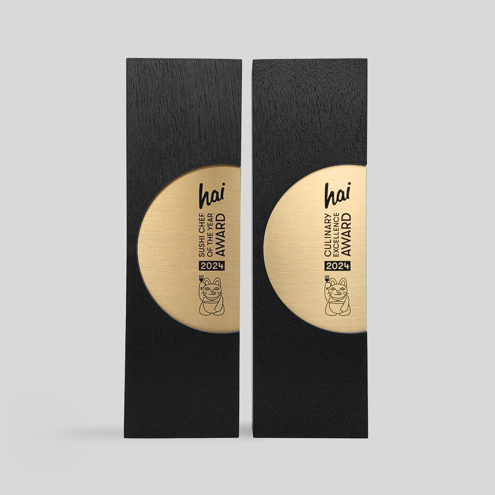 Figura Ellipsum Award, featuring a circular design, black and gold accents, with a cat and fork motif, symbolizing commitment and harmonious relationships.