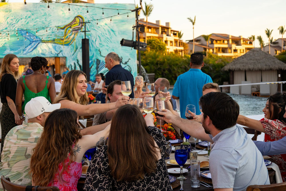 Group of people enjoying a meal and drinks by a poolside with a mural in the background before the Zayo President's Club award presentation.