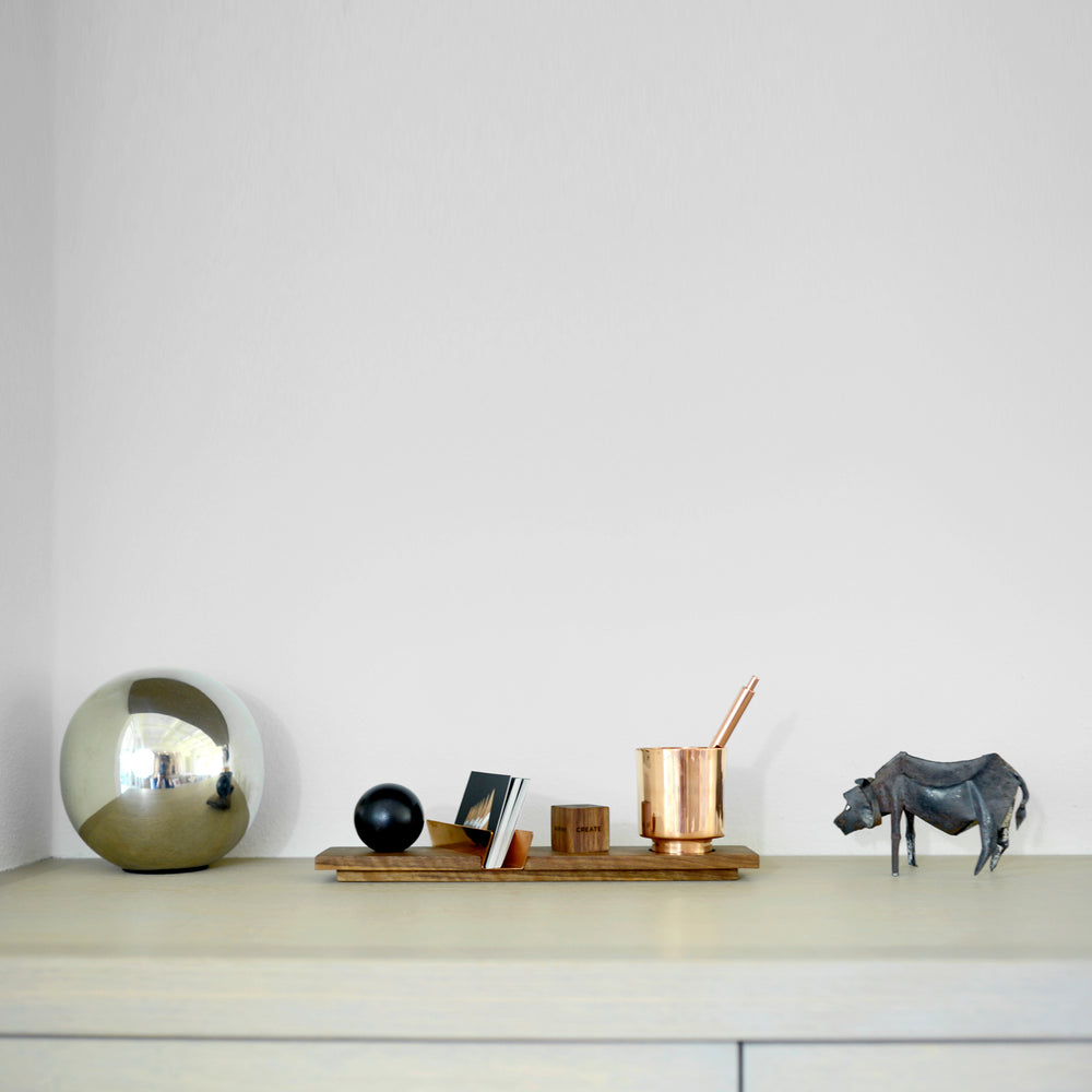 Desk Accessory Lux Cupri featuring a walnut base, copper cup, ebony sphere, and metal cow statue, capturing elegance and multifunctional design.