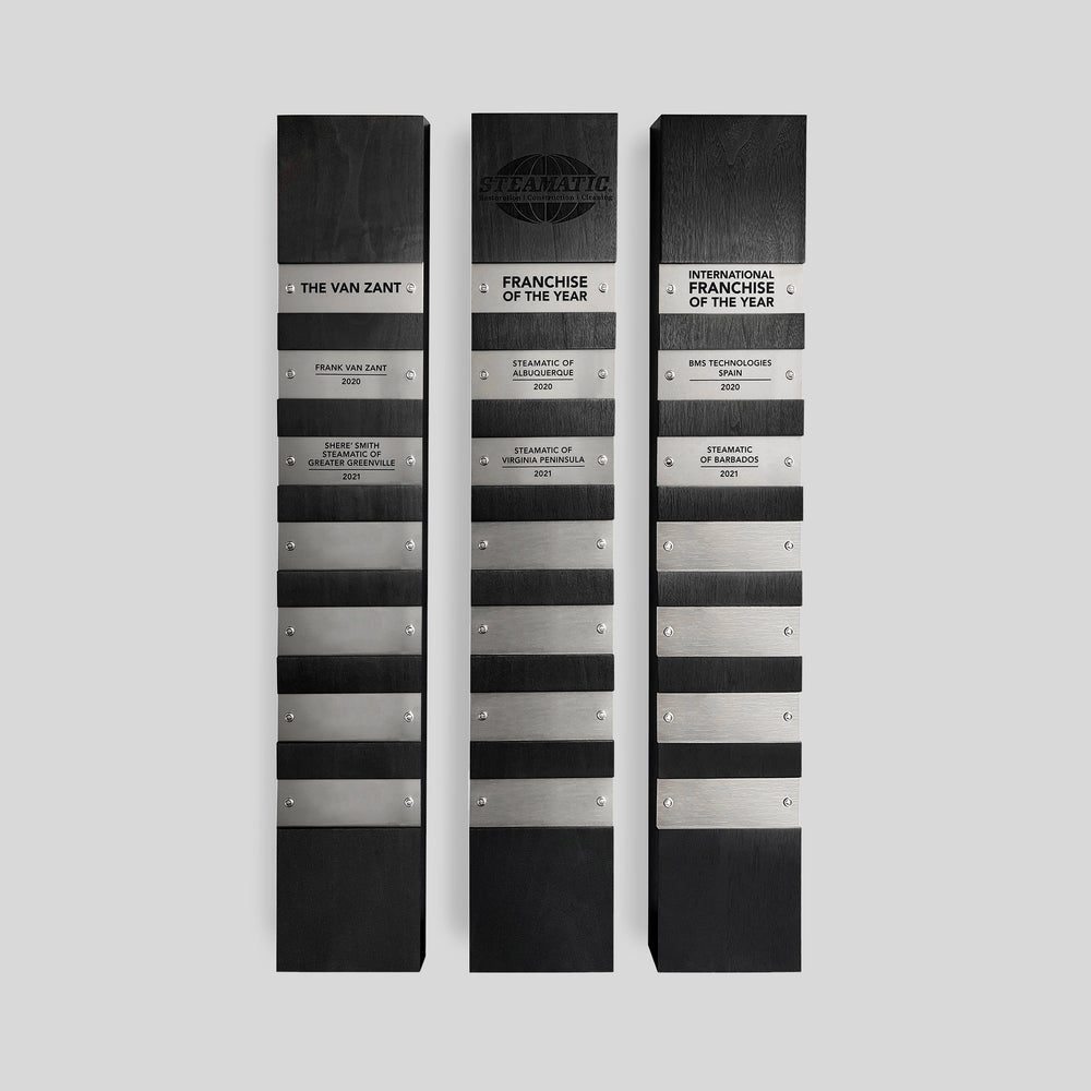 Perpetual Plaques | Ebony wood award plaque installation featuring metal nameplates, engraved with annual honorees, engraving on wood with logo, ideal for personalized engraving and elegant lobby recognition displays for companies and organizations. 