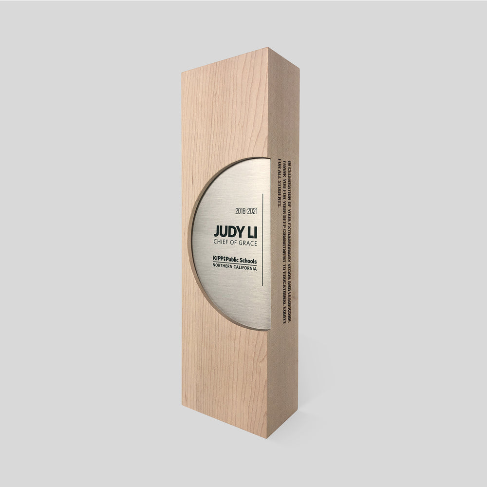Figura Ellipsum Award in a wooden box features a circular silver plaque, symbolizing commitment and community, crafted with walnut, maple, and metal accents.