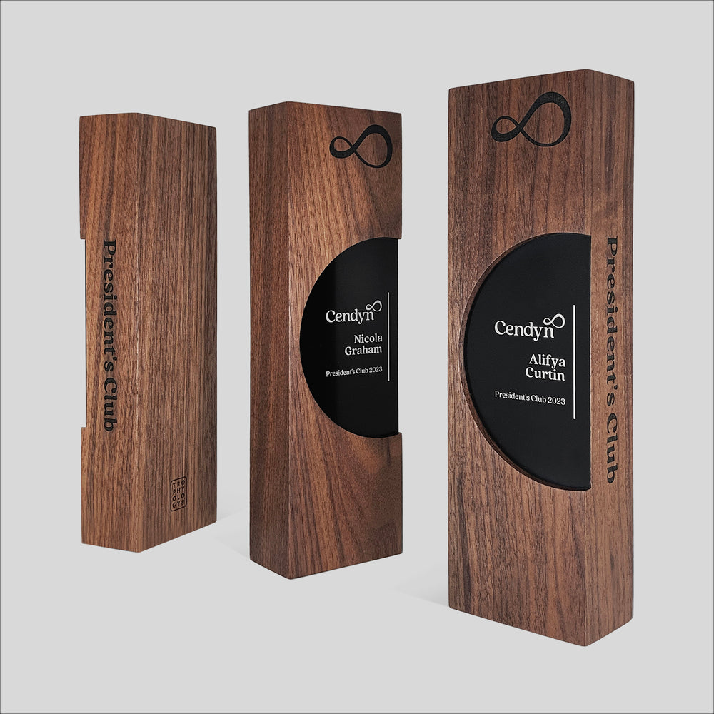 Figura Ellipsum Award, a rectangular wooden box with a black circular design, symbolizes continuity and community, blending walnut and maple for a tactile, elegant recognition piece.