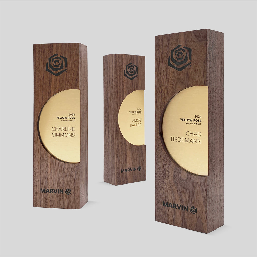 Figura Ellipsum Award featuring engraved gold plaques on wooden bases, showcasing minimalist circular design symbolizing continuity and community, crafted with walnut and maple.