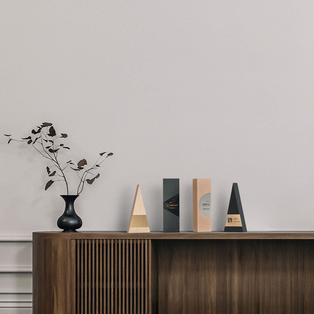 Unique employee recognition awards crafted from wood and metal on a wooden sideboard in an office space