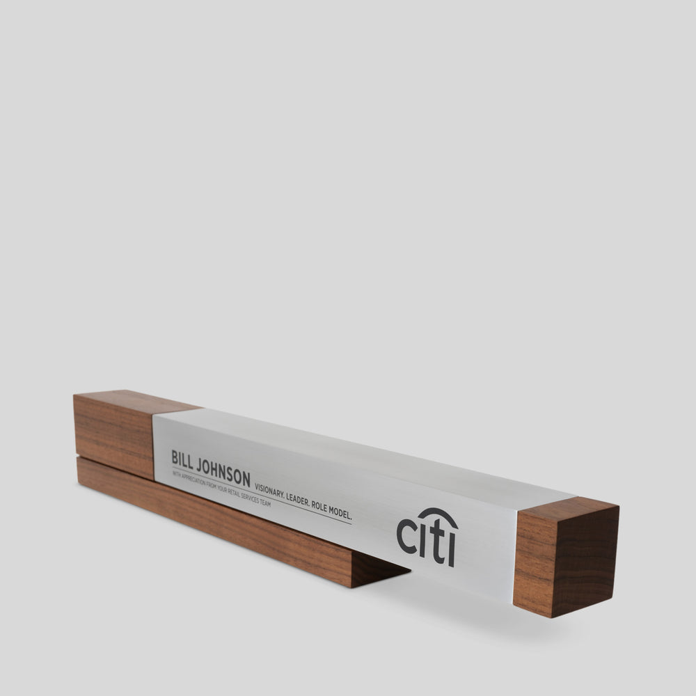 Fulgeo Award showcasing a cantilevered aluminum beam on a walnut base, symbolizing innovation and strength, with a silver and black logo displayed prominently.